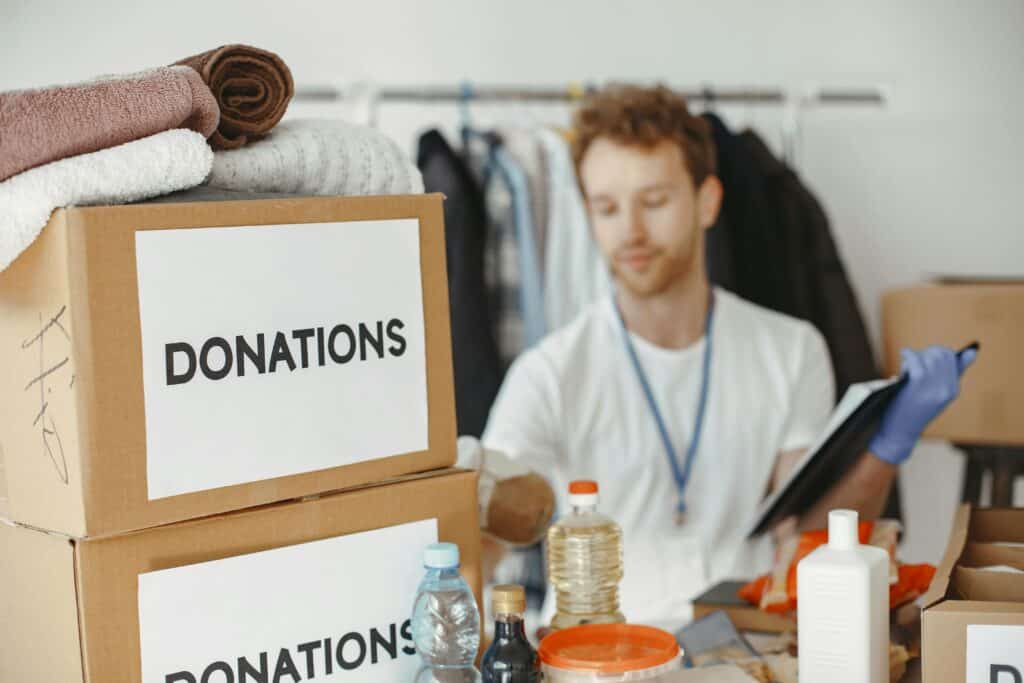 Volunteer organizing donation boxes with clothes and supplies for charity.